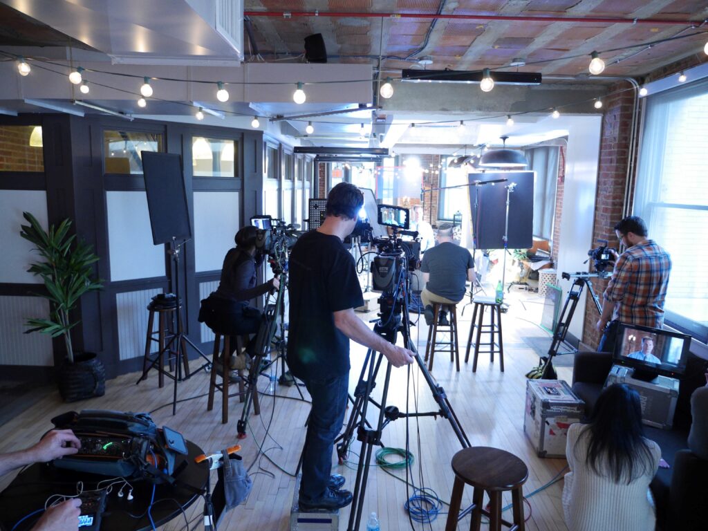 Braun professional film and video production set in progress in a studio with professional cameras setup on tripods.