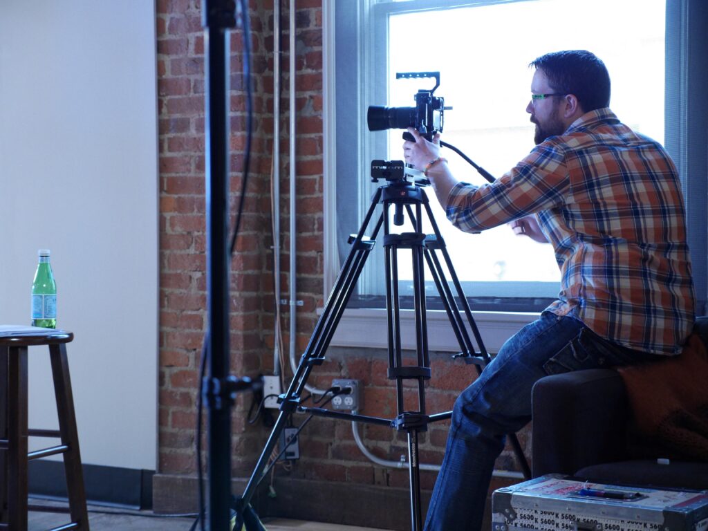 A professional videographer using a professional video camera with an E-Image 2-stage video tripod kit.