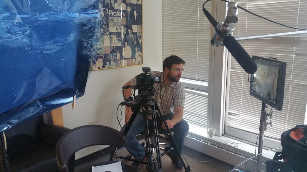 Camera operator setting up a corporate interview shoot with a boom mic and field monitor