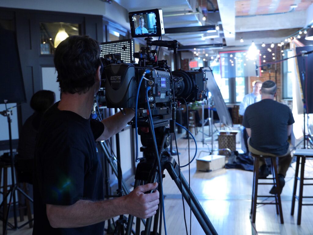 Braun video production crew with professional video cameras and lights, filming a host on a live TV show.