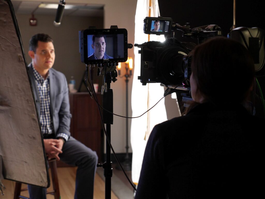Braun video production crew with professional video cameras and lights, filming a host on a live TV show.